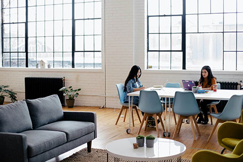 Two girls working while sitting on the table